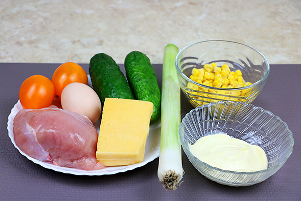 Поживний салат із курятини, твердого сиру, свіжого огірка, помідорів, цибулі порей, кукурудзи, яйця