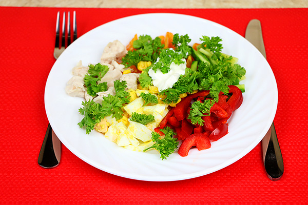 Барвистий салат з курячого філе, червоного перцю, огірків, яєць, помідорів та кукурудзи 